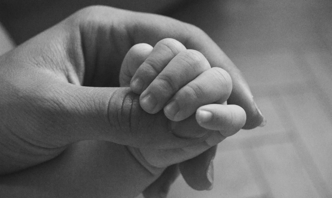 Black and white photo of baby's hand in mother's