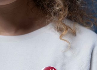 vote button on woman wearing white sweatshirt, with curly hair
